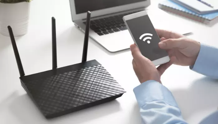 Man using a mobile sitting near wifi modem