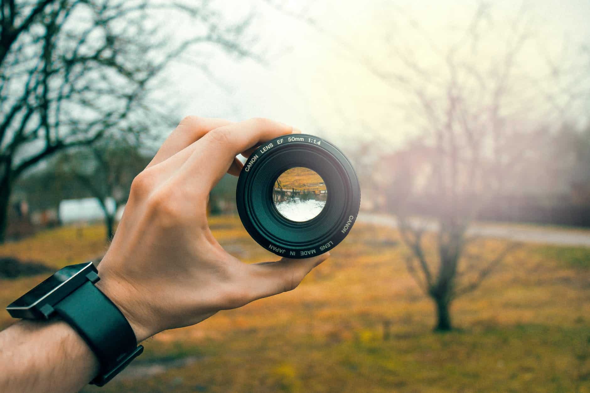 photography of person holding black camera lens - photography gadgets