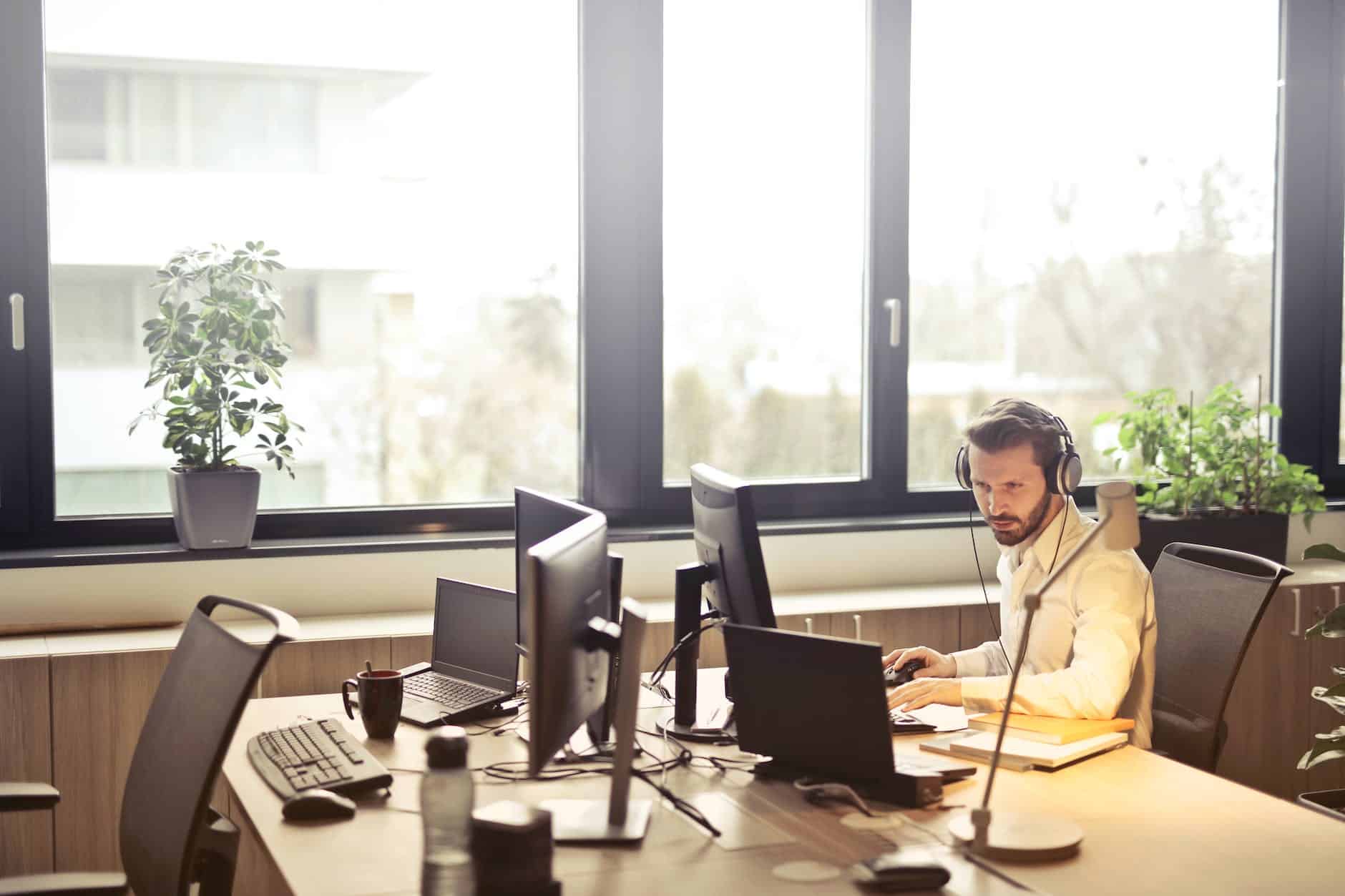 man with headphones facing a computer monitor - IT Support