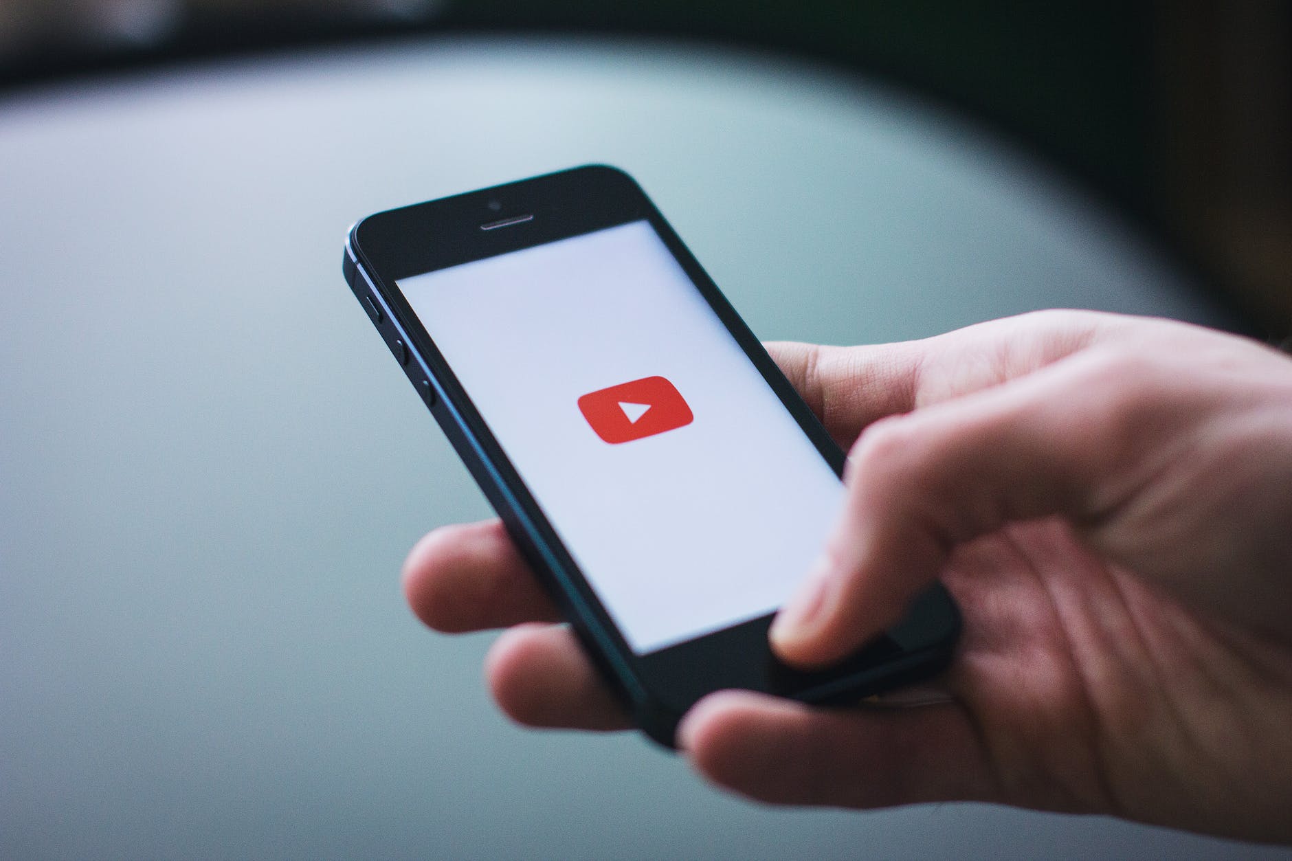 A male hand is holding a smartphone on which YouTube is opening - Social Media Videos