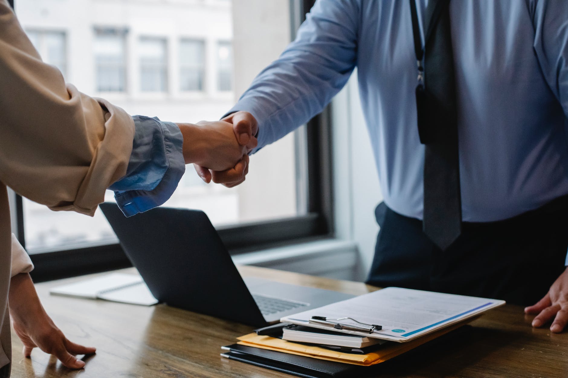 crop colleagues shaking hands in office Best Insurance Company To Be An Agent For